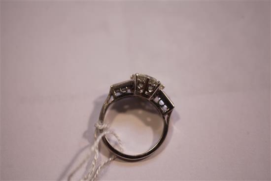 An early to mid 20th century platinum and single stone diamond ring with baguette cut diamond set shoulders, size I.